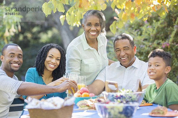 Porträt der glücklichen Mehrgenerationen-Familie beim Mittagessen auf der Terrasse