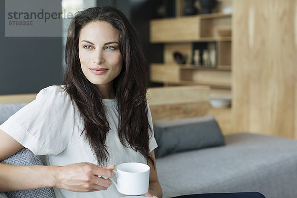 Frau trinkt Kaffee im Wohnzimmer