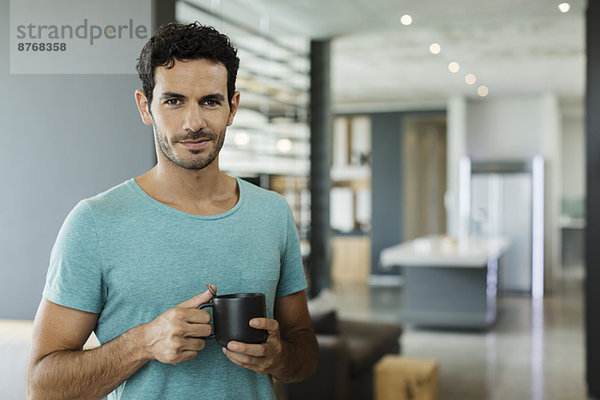 Porträt eines lächelnden Mannes beim Kaffeetrinken zu Hause