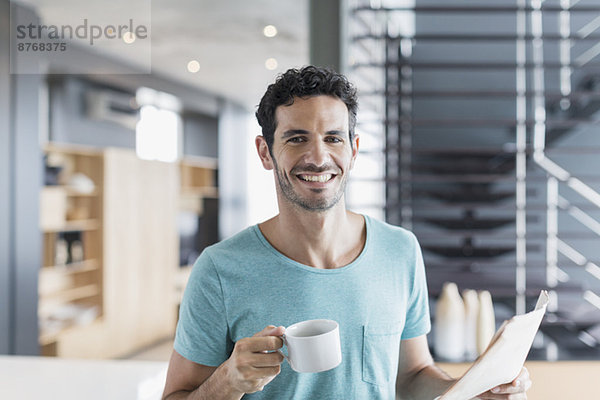 Porträt eines lächelnden Mannes beim Kaffeetrinken zu Hause