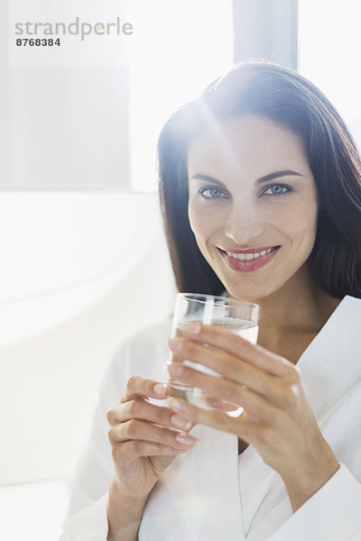 Porträt der lächelnden Frau im Bademantel Trinkwasser