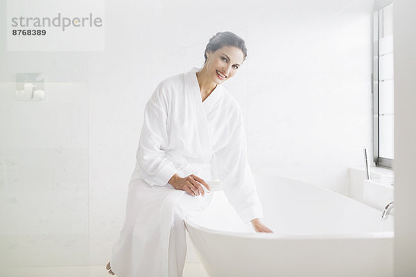 Porträt der lächelnden Frau im Bademantel beim Vorbereiten des Bades