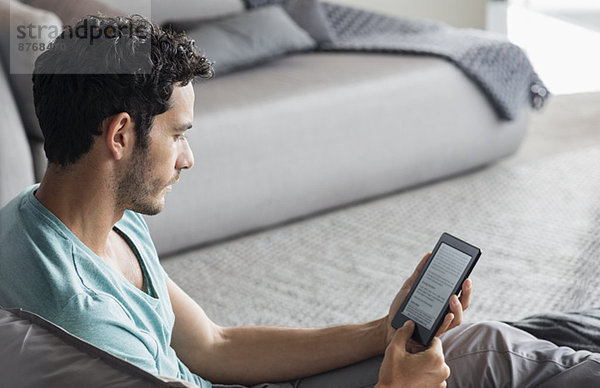 Mann mit digitalen Tablette im Schlafzimmer