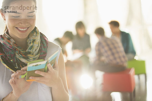 Glückliche Geschäftsfrau SMS mit Handy außerhalb des Meetings