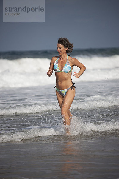 Griechenland  Kreta  Reife Frau im Wasser laufend
