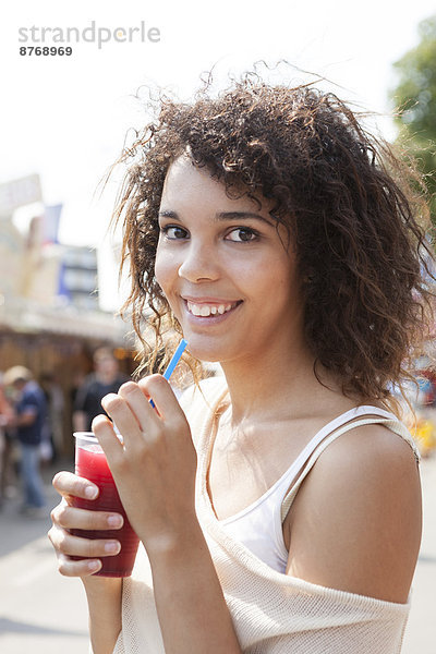 Junge Frau auf dem Jahrmarkt trinkt Saft  Porträt
