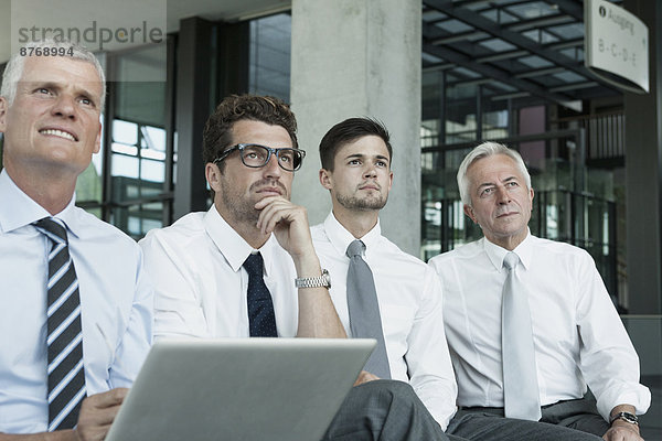 Vier Geschäftsleute sitzend mit Laptop