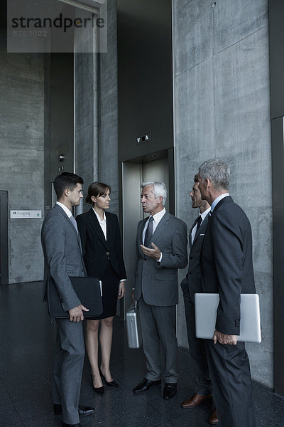 Gruppe von Geschäftsleuten diskutiert am Aufzug
