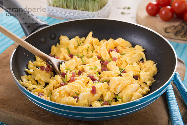 Scrambled eggs with ham cubes in frying pan