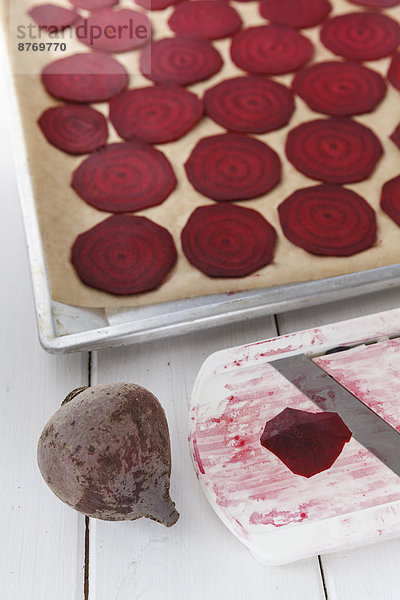 Backblech mit Rübenscheiben  Küchenbrett  Messer und Rote Beete