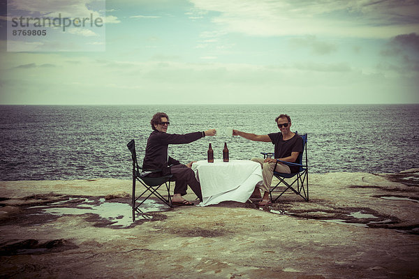 Australien  Sydney  zwei Männer sitzen mit Bier am Tisch auf Klippe
