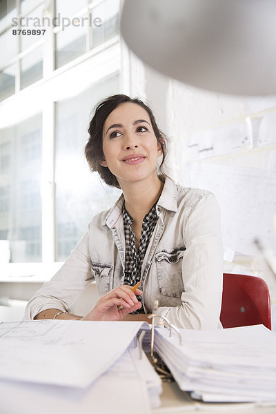 Porträt einer jungen Architektin an ihrem Schreibtisch im Büro