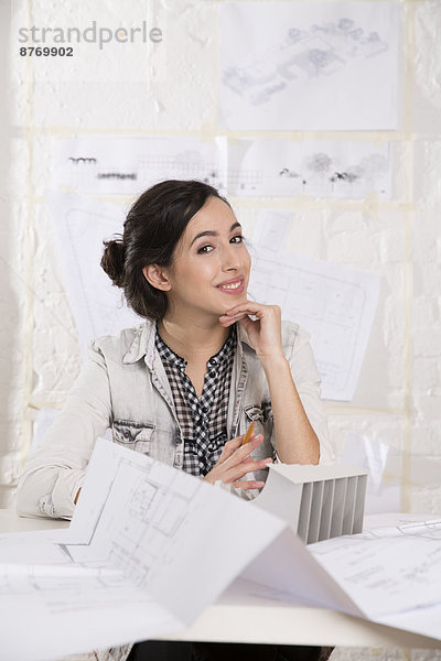 Portrait of young female architect sitting at her desktop in office