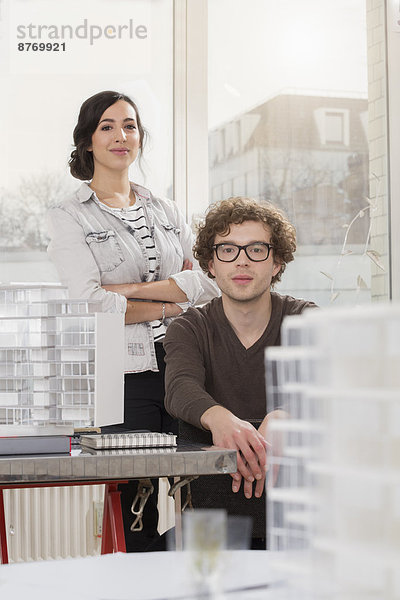 Porträt zweier junger Architekten mit Architekturmodell im Büro