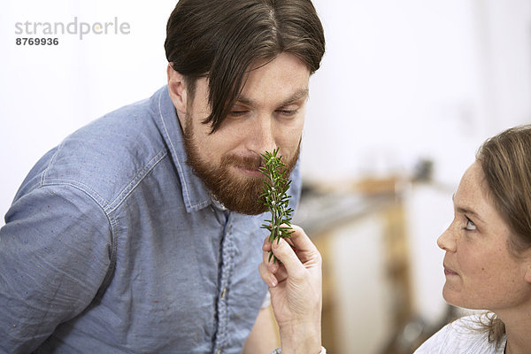 Man smelling at twig of rosemary