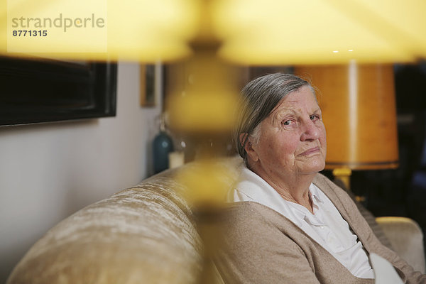 Seniorin sitzend auf einer Couch im Wohnzimmer