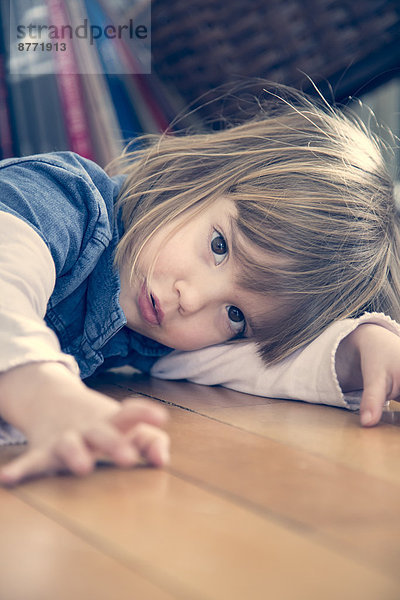 Porträt eines kleinen Mädchens auf dem Boden liegend