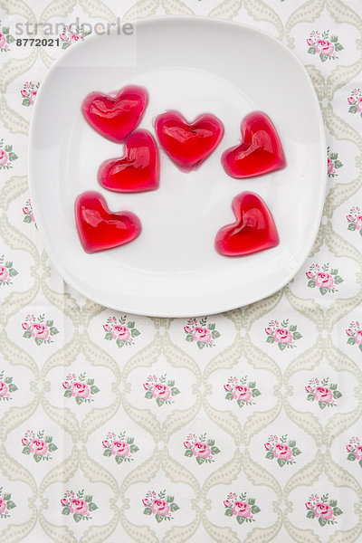 Teller mit roten Herzen in Form von Kirschgelee auf Tuch