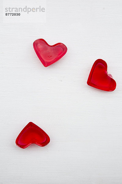Drei rote Herzen in Form von Kirschgelee auf weißem Grund