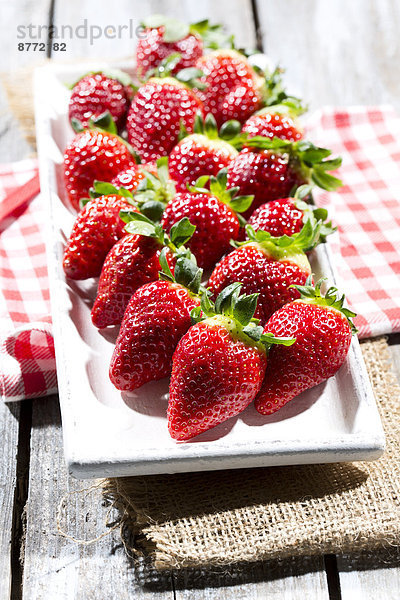 Platter of strawberries (Fragaria) on jute  kitchen towel and wooden table