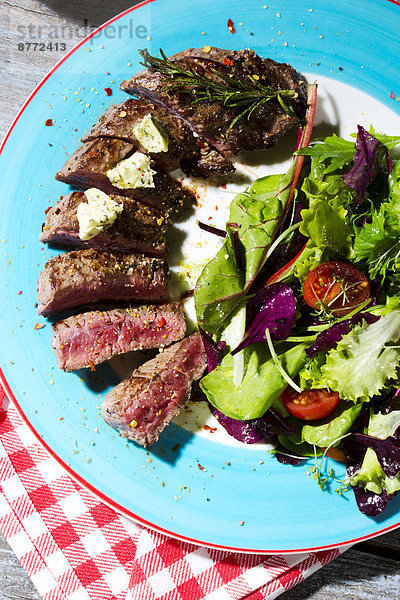 Beef sirloin steak with rosemary  garlic  herb butter  pepper and salad