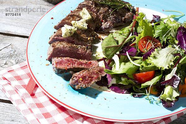 Beef sirloin steak with rosemary  garlic  herb butter  pepper and salad