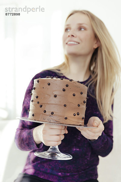 Junge Frau hält Kuchenstand mit Schokoladenkuchen