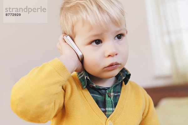 Porträt eines ernsthaft aussehenden Kleinkindes beim Telefonieren mit dem Smartphone