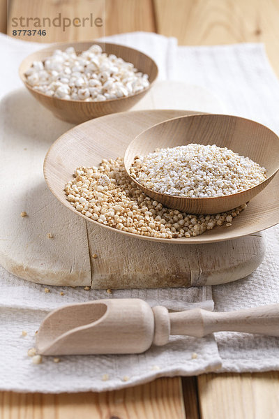 Bowls of puffed buckwheat  amaranth and quinoa on wooden board and kitchen towel