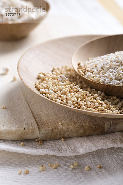 Bowls of puffed buckwheat  quinoa and amaranth on wooden board and kitchen towel