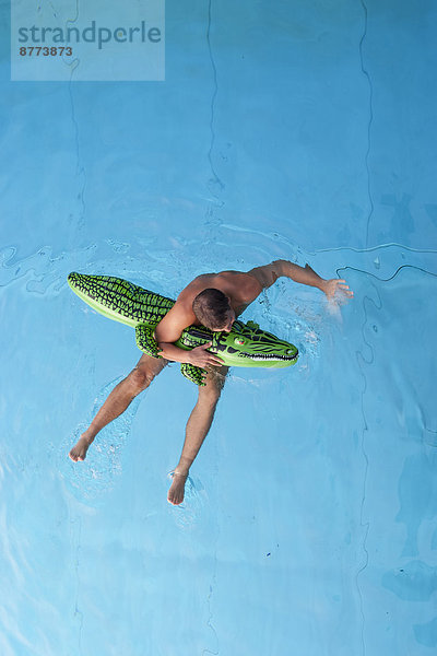 Young man with swim toy floating in water  view from above