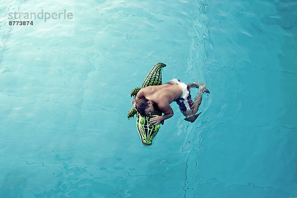 Young man with swim toy floating in water  view from above