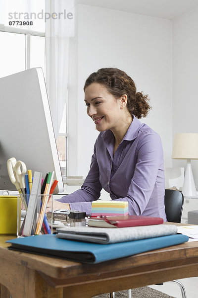 Woman at home sitting at desk with computer