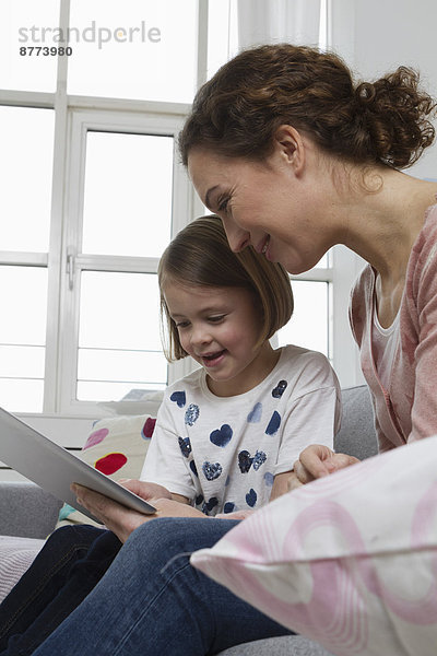 Mother and daughter on couch with tablet computer