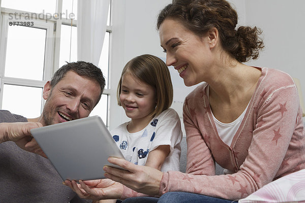 Mutter  Vater und Tochter auf Couch mit Tablet-Computer