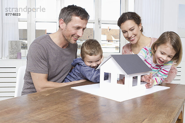 Family of four looking at house model