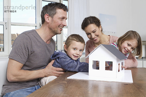 Vierköpfige Familie mit Blick auf das Hausmodell