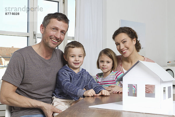 Vierköpfige Familie mit Hausmodell