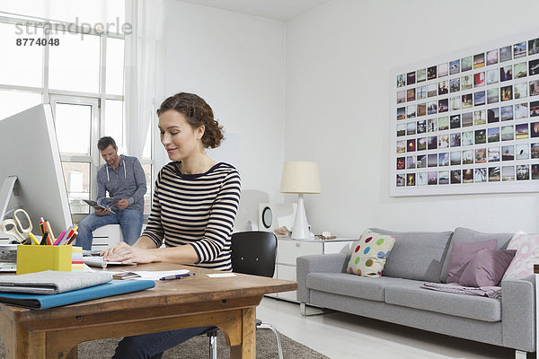 Man and woman at home sitting at desk with computer