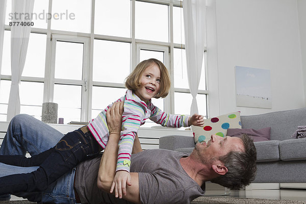 Playful father and daughter in living room