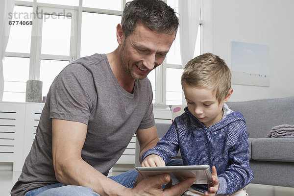 Vater und Sohn mit Tablet-Computer im Wohnzimmer