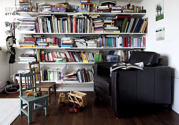 Bücherregal und Spielzeug im Zimmer mit Sessel und Stühlen
