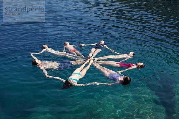 Familiengruppe von acht Personen  die im Kreis auf See schweben