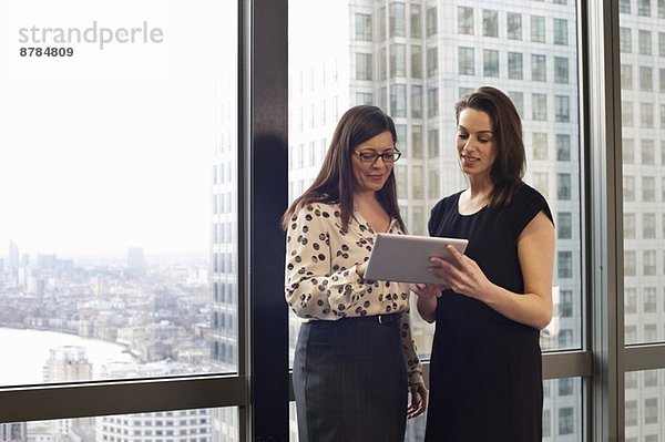 Weibliche Geschäftskolleginnen beim Betrachten des digitalen Tabletts im Büro