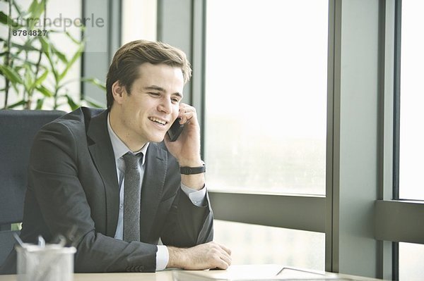 Junger Geschäftsmann im Gespräch mit dem Smartphone aus dem Büro