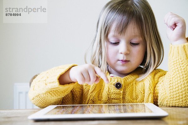 Junges Mädchen am Küchentisch mit digitalem Tablett