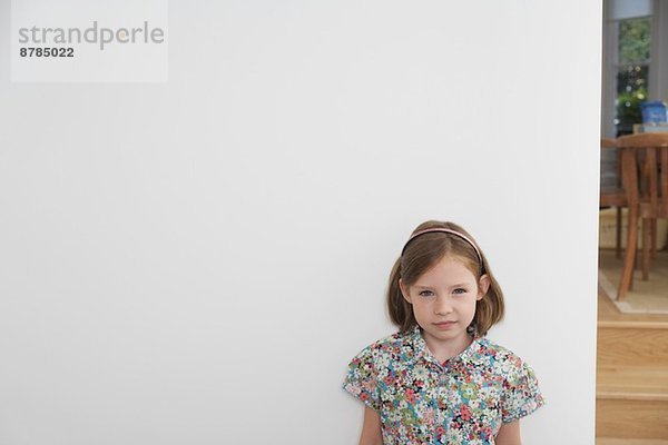 Porträt des schüchternen Mädchens neben der weißen Wand