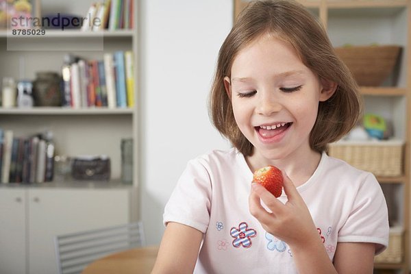 Junges Mädchen in der Küche mit einer frischen Erdbeere