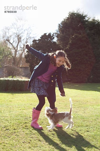 Mädchen beim Spielen im Garten mit ihrem Hund