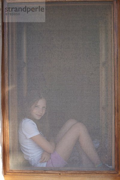 Porträt eines Mädchens im verdeckten Fensterrahmen